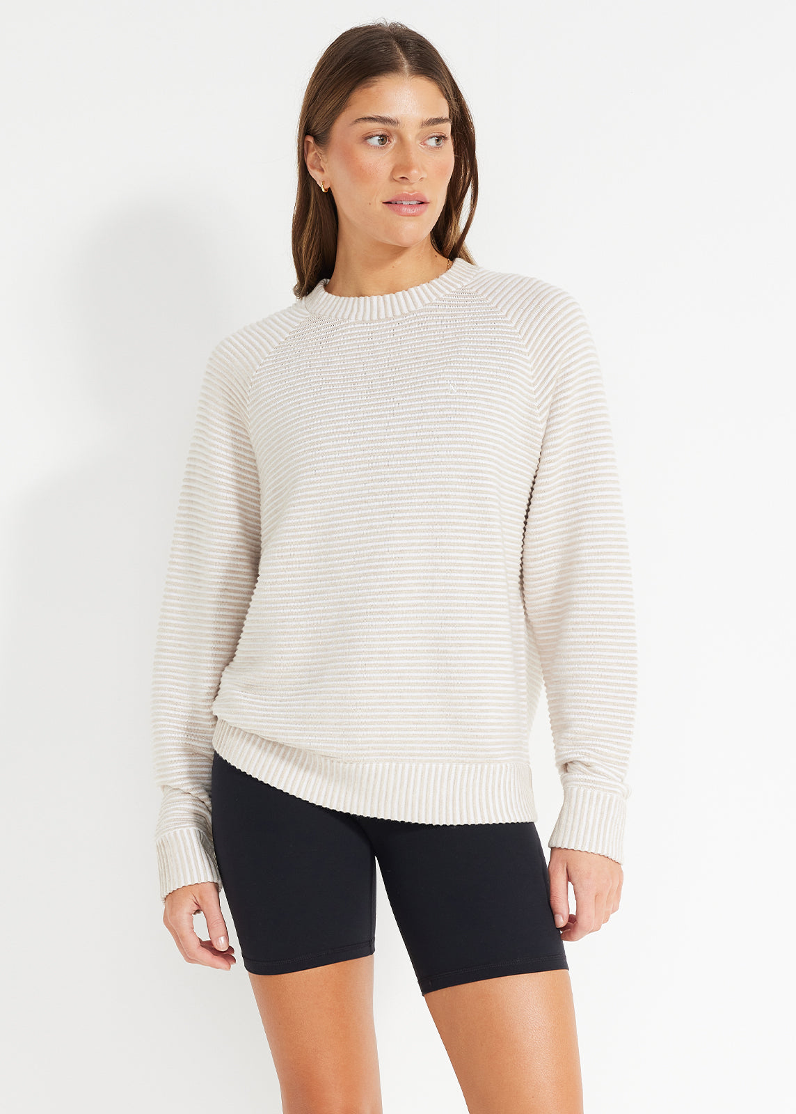 Model wearing beige and white striped crewneck jumper with black bike shorts