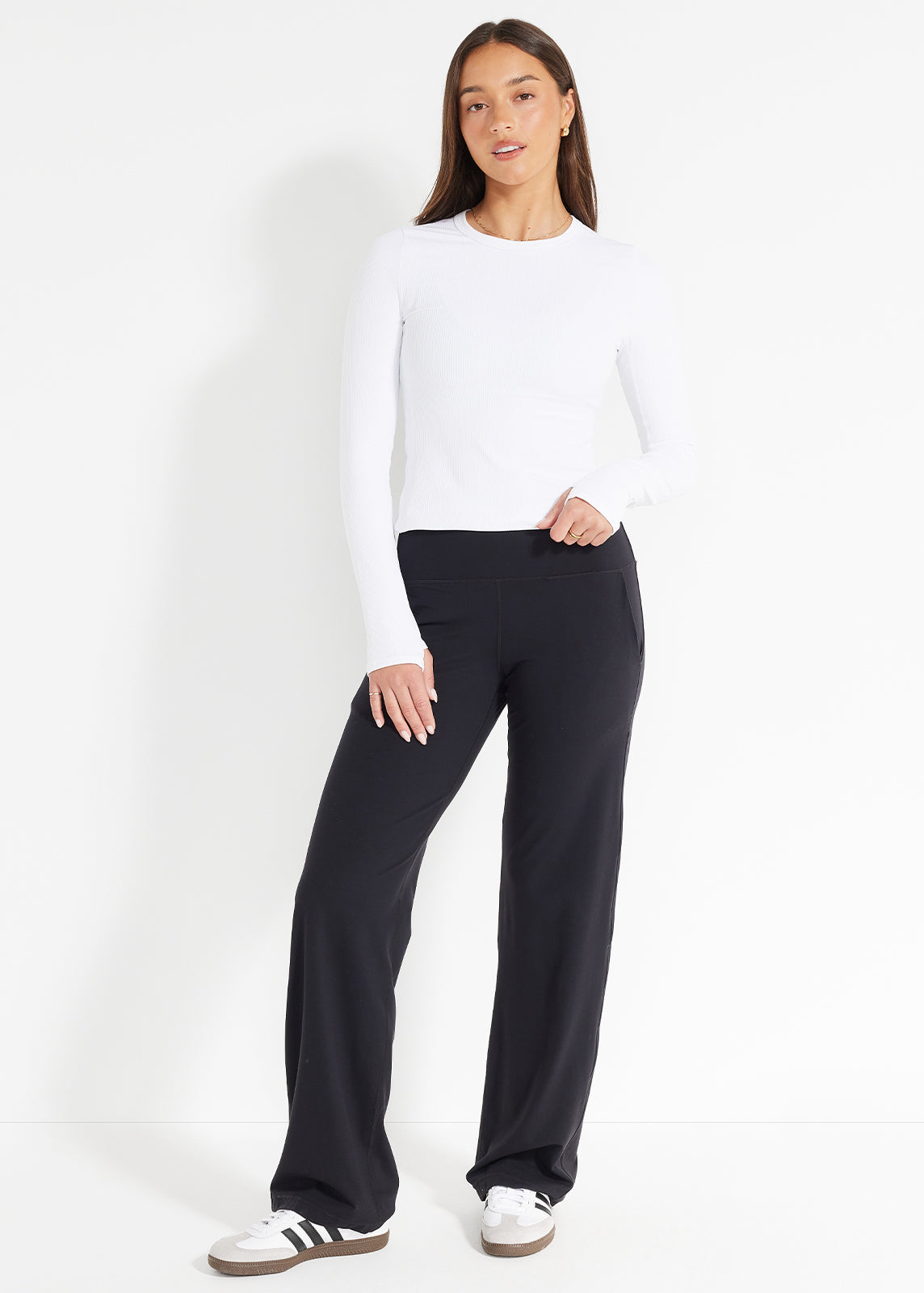 Product image showing model in white long-sleeve top and black wide-leg pants with hands in pocket