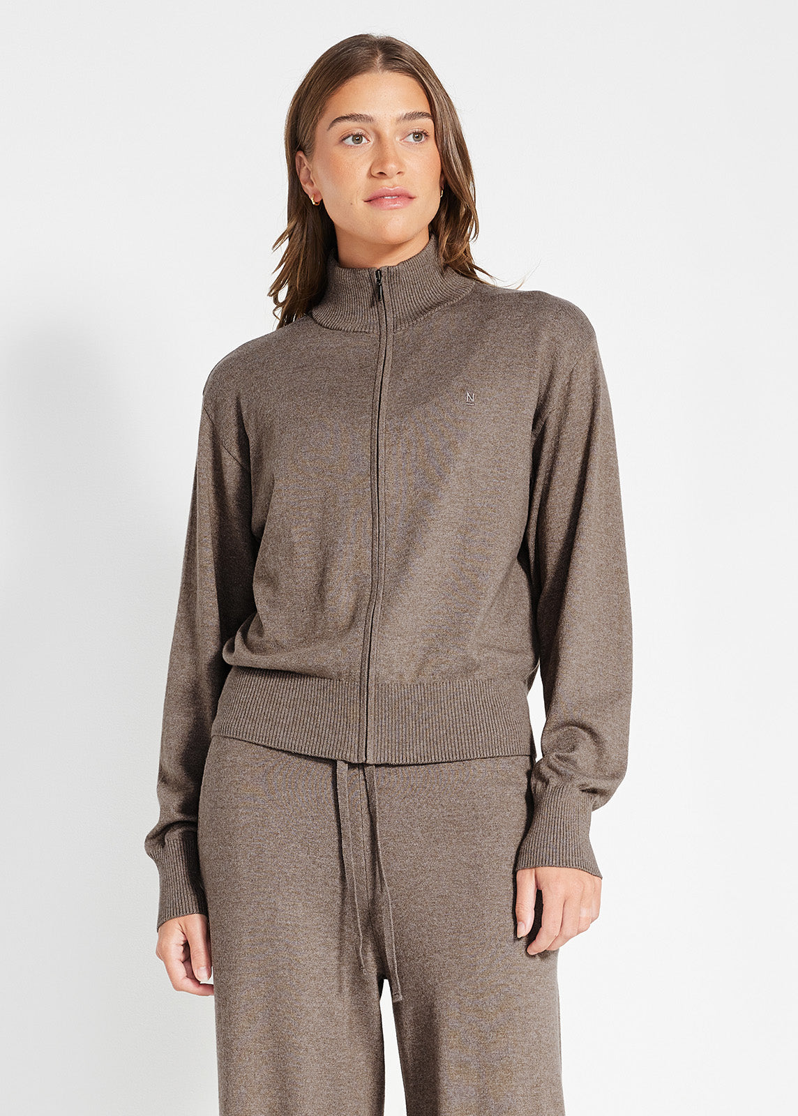 Model wearing a brown zip-up knit jacket with ribbed cuffs and waistband, paired with matching lounge pants