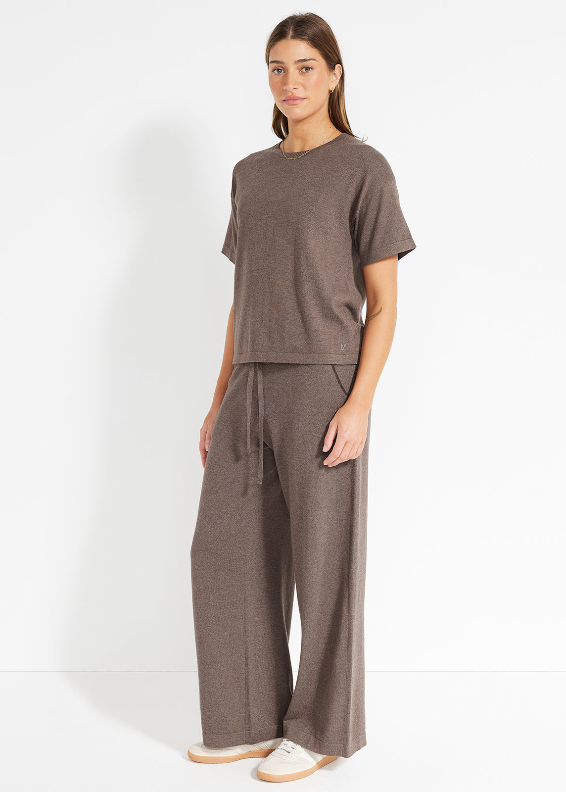 Model wearing brown knit T-shirt and matching wide-leg pants with white sneakers