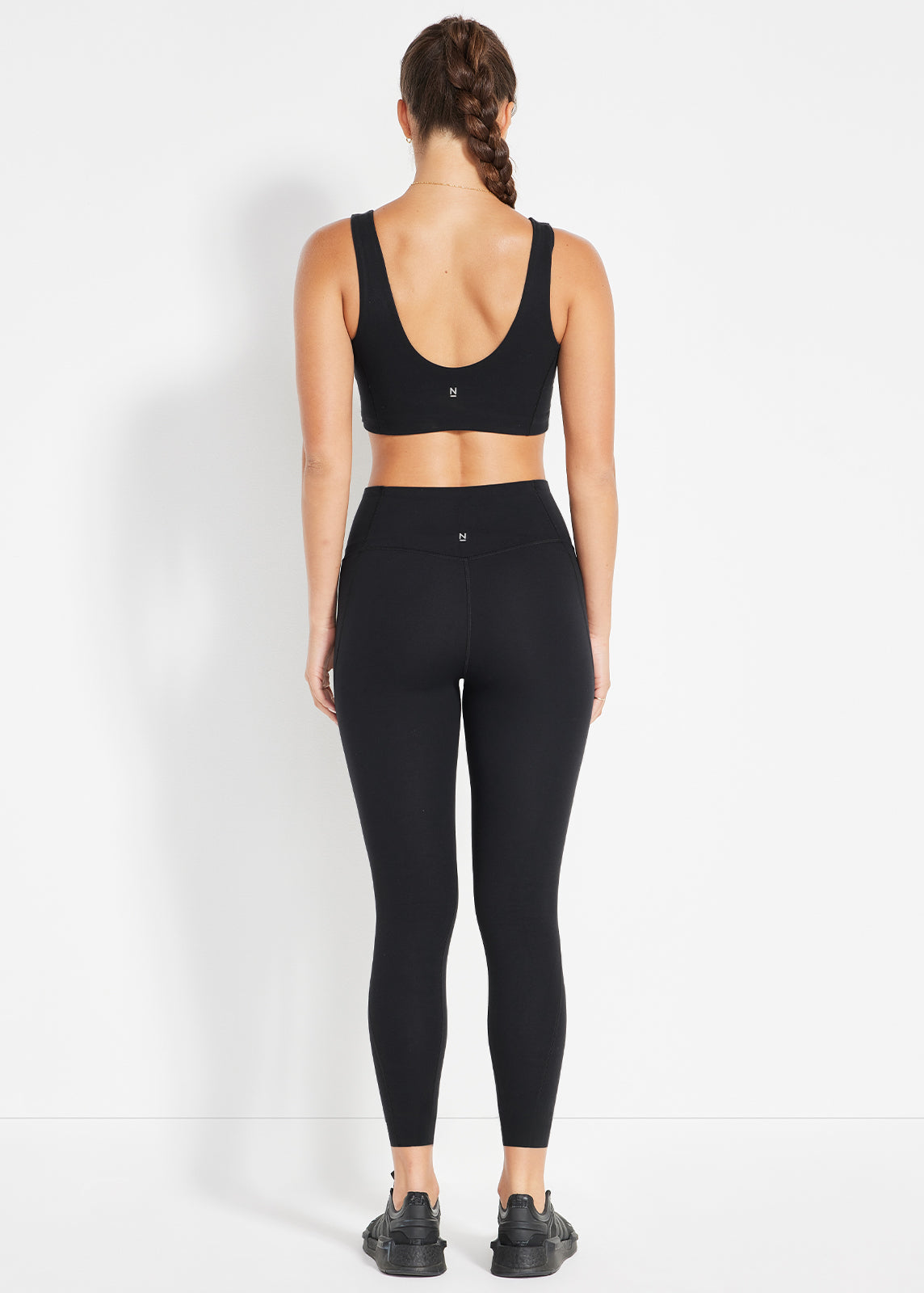 Back view of model wearing black scoop sports bra and high-rise leggings
