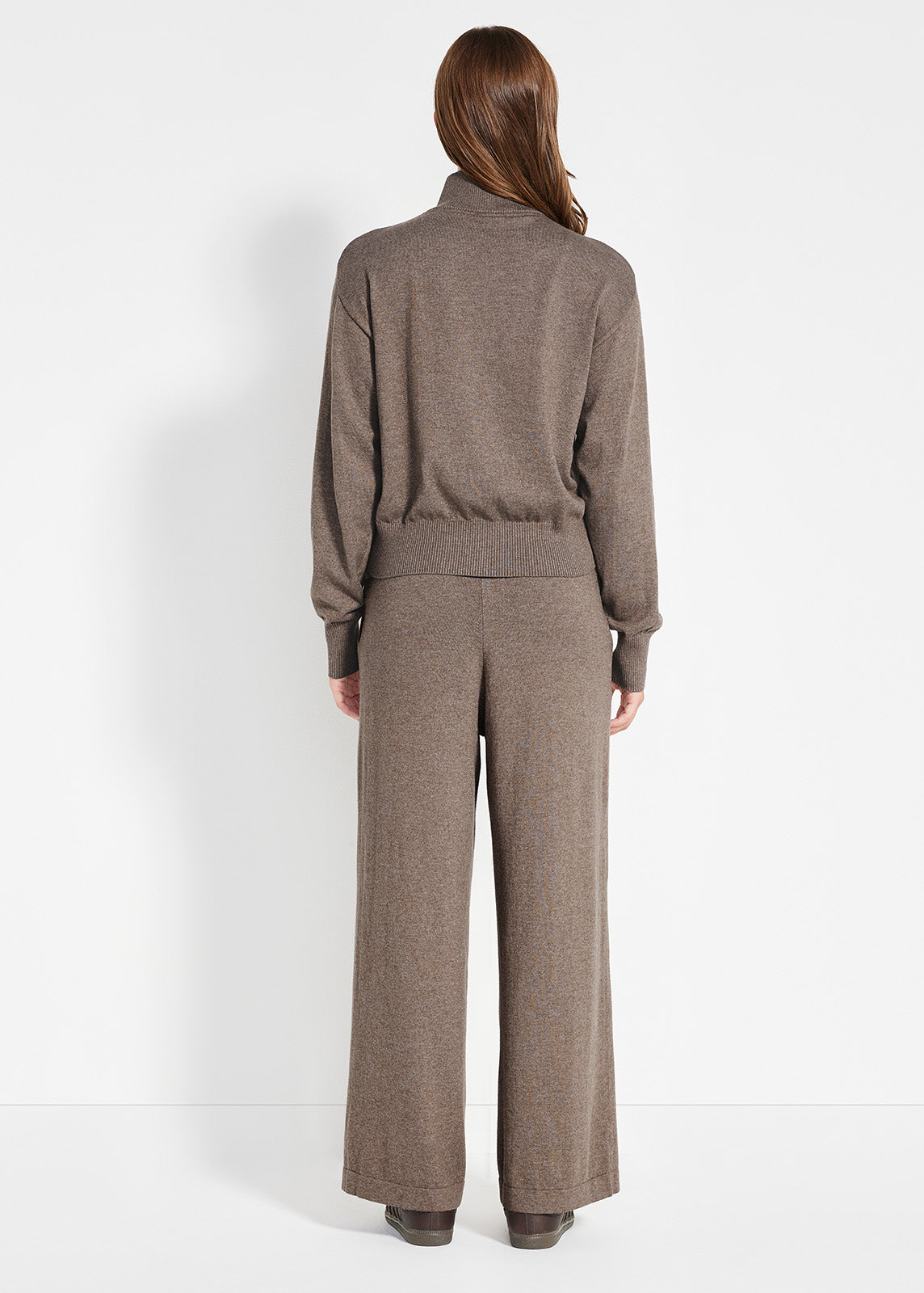 Model wearing brown knit zip-up jacket and matching wide-leg pants styled with brown sneakers