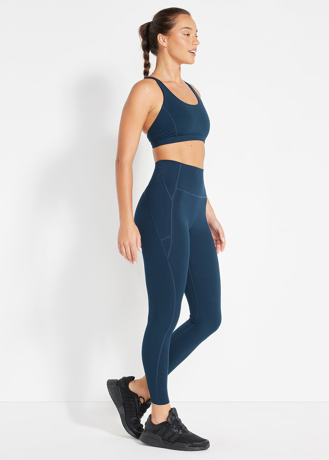 Side profile of navy scoop bra and high-rise leggings styled with black sneakers