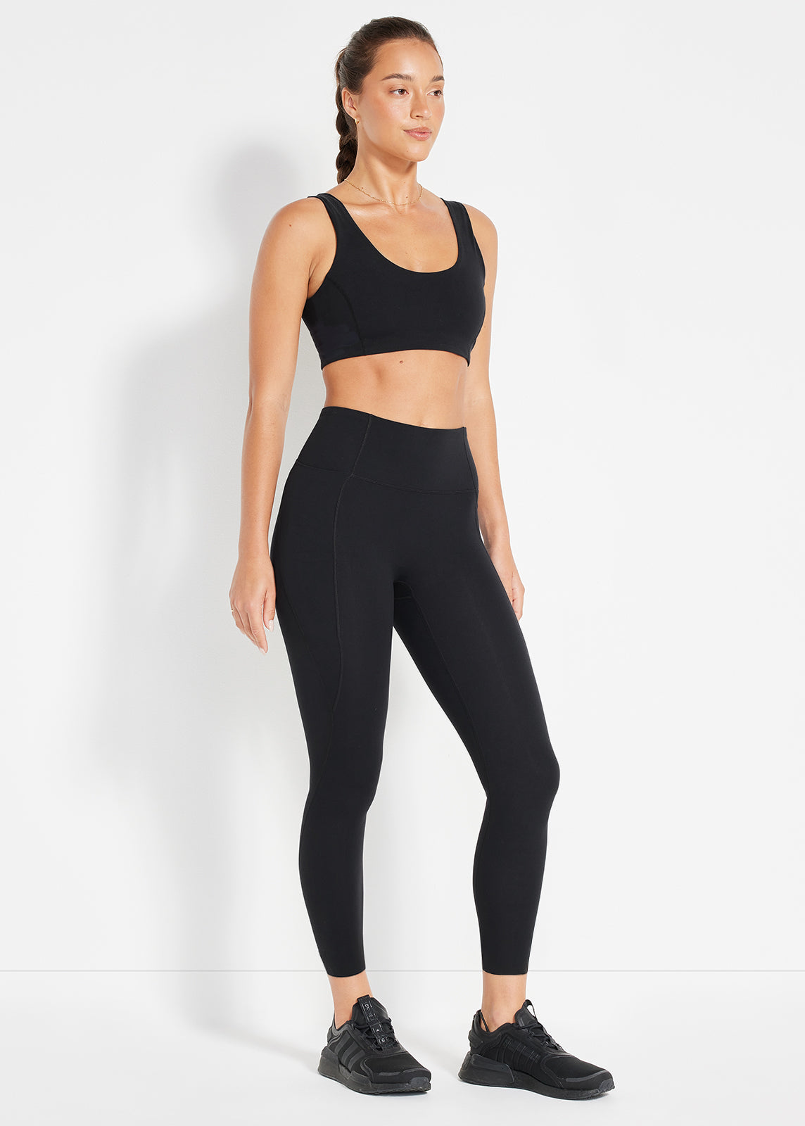 Model wearing black sports bra and high-rise leggings in studio