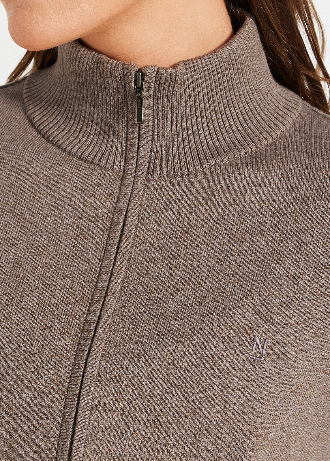 Close-up of brown ribbed zip-up knit jumper with embroidered logo