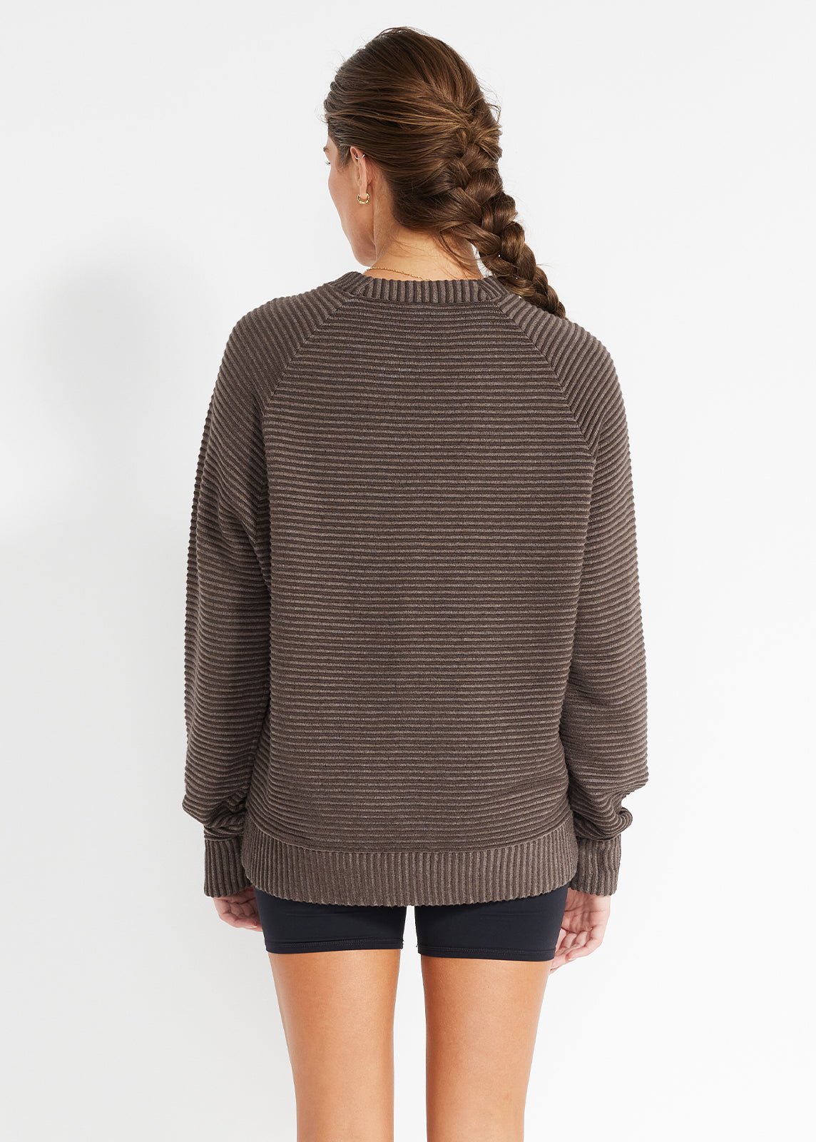 Back view of model wearing brown ribbed knit jumper styled with black bike shorts