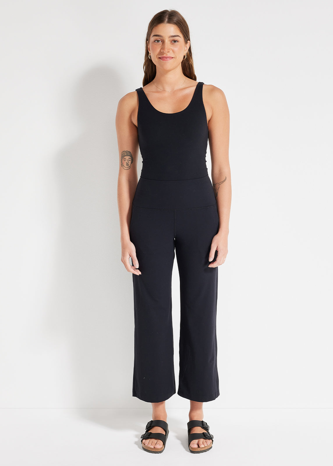 Model wearing black scoop tank and cropped wide-leg pants in studio