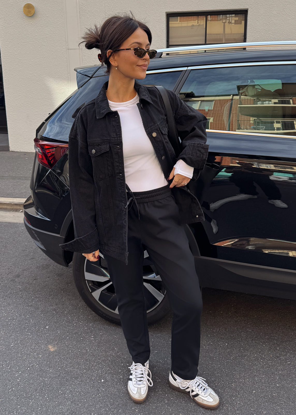 Street style look featuring black jogger pants, white top and denim jacket