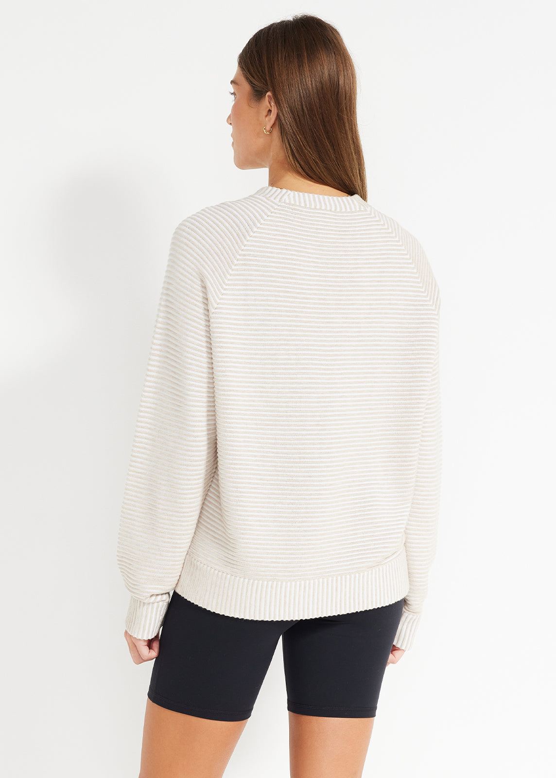 Back view of beige and white striped crewneck jumper paired with black bike shorts