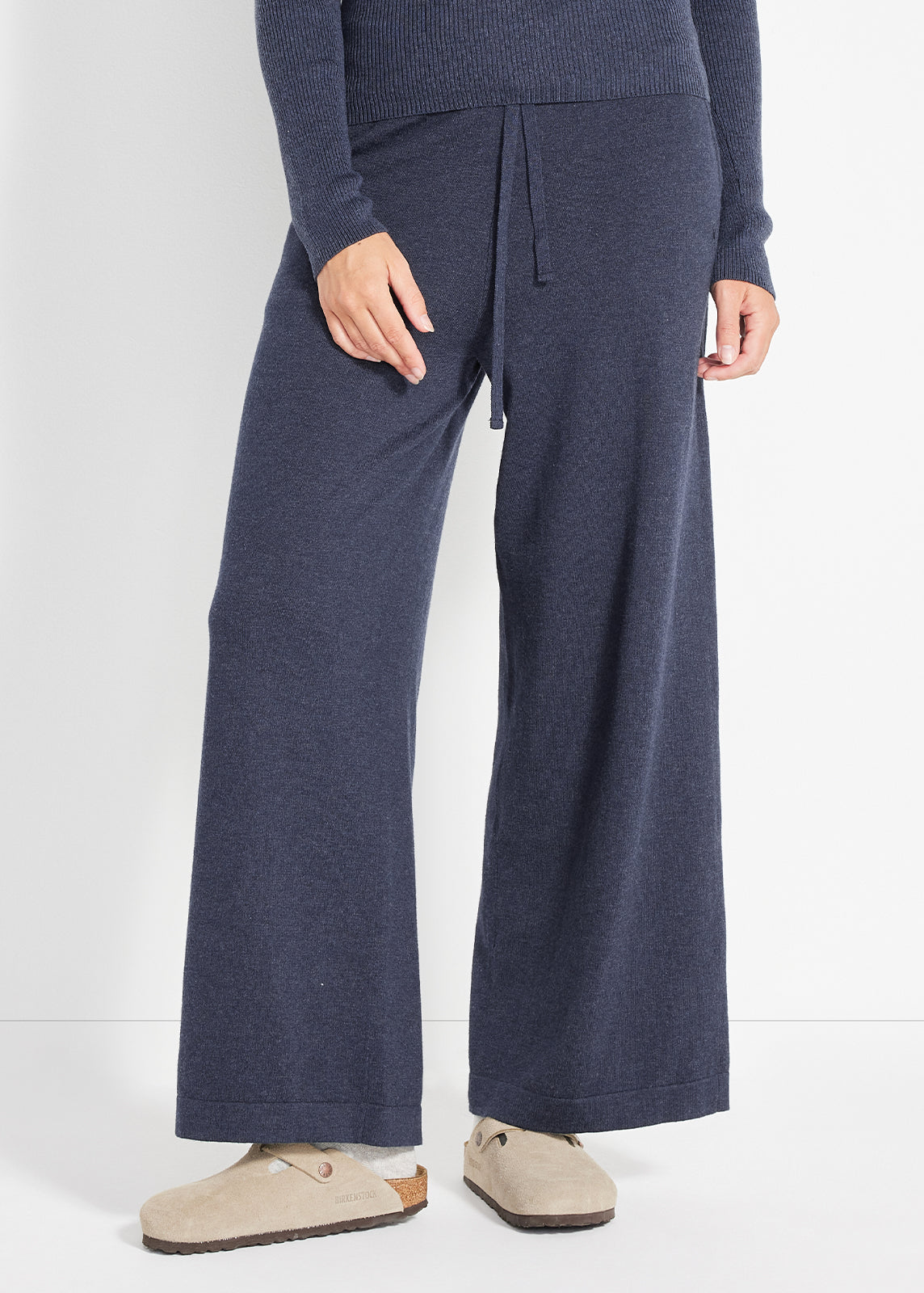 Close-up of navy ribbed lounge pants showing relaxed wide-leg fit and drawstring waistband