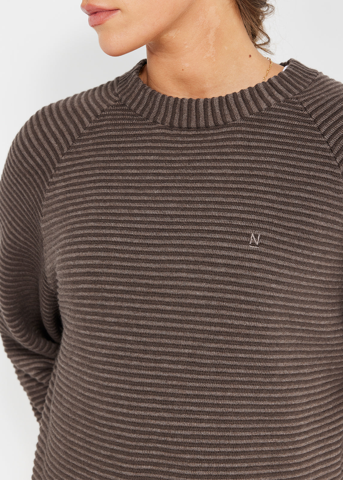 Close-up of brown striped ribbed knit jumper with tonal embroidered logo