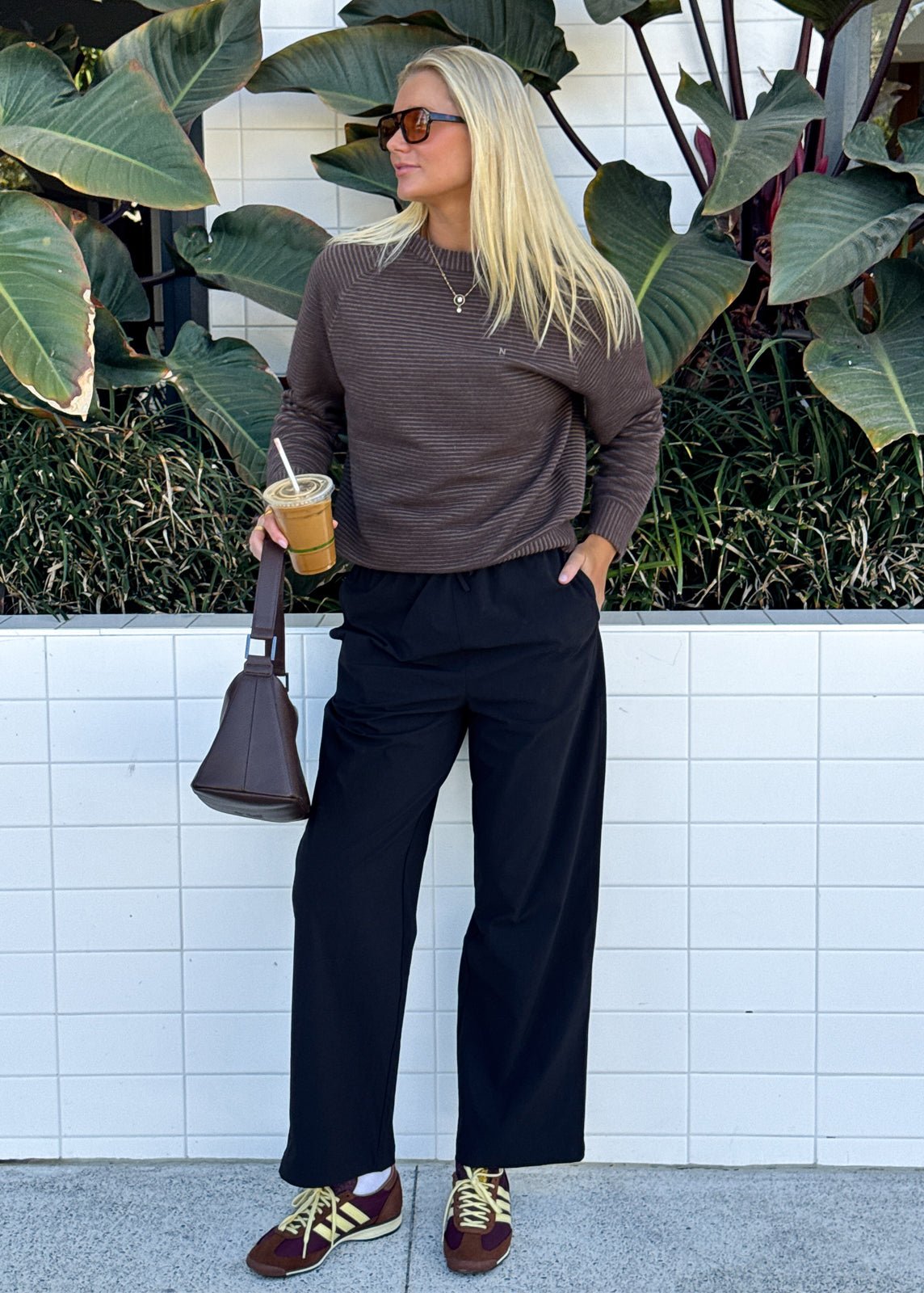 Model wearing brown knit lounge set layered with white fleece vest and striped jumper