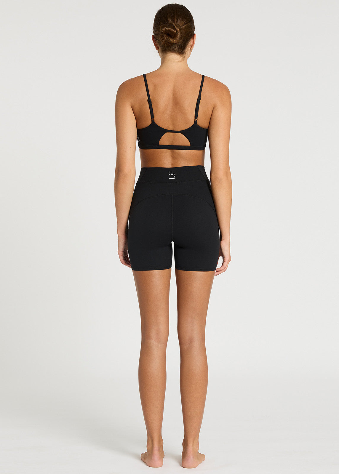 Model stood facing backwards wearing black bike shorts with V-waistband and white logo detail to the back.
